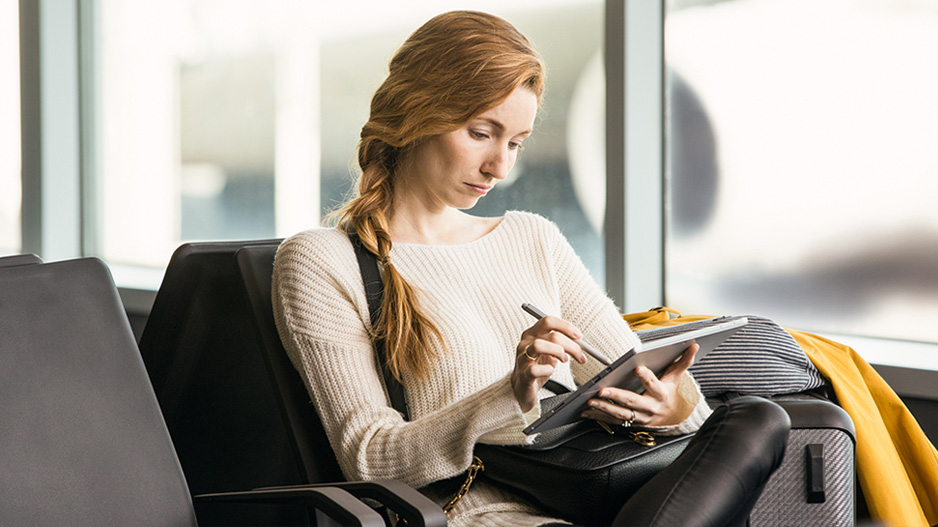 一个人正坐在等候室里使用 Surface 触控笔。