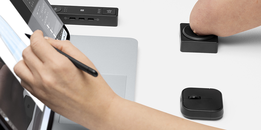 一位残疾人士借助 Microsoft 自适应方向键按钮和集线器使用 Surface 设备。