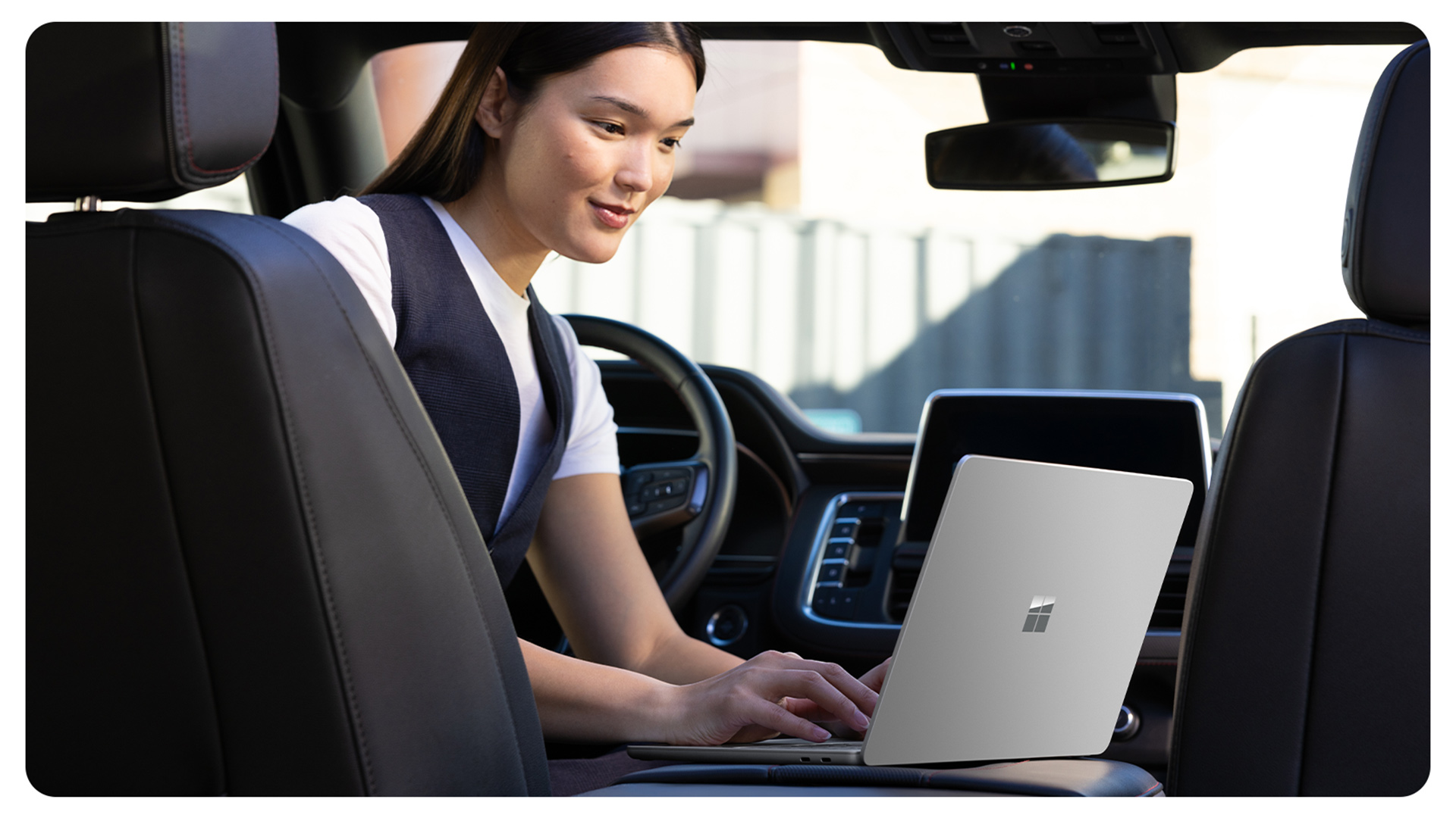 一位停留在车内的人正在使用 Surface Laptop 商用版，展示了防反射屏幕如何让人在各种环境中都能轻松使用该设备。