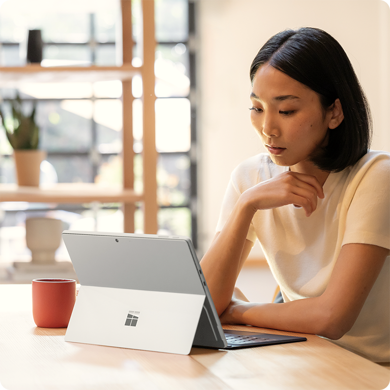一位用户坐在桌前，使用搭配了 Surface Pro 13 英寸 Flex 键盘盖的 Surface Pro 商用版办公。