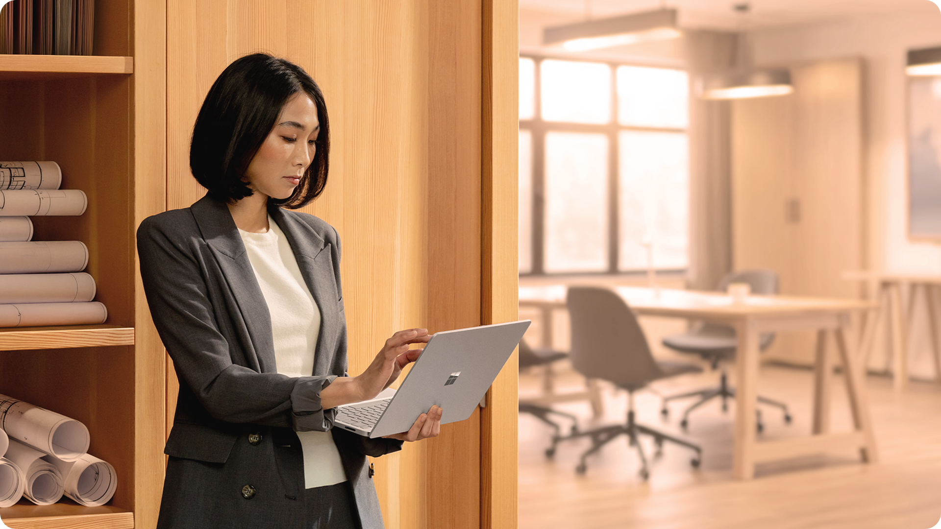 人物同时携带并使用 13.8 英寸的 Surface Laptop 商用版，直观展现该设备的便携性。