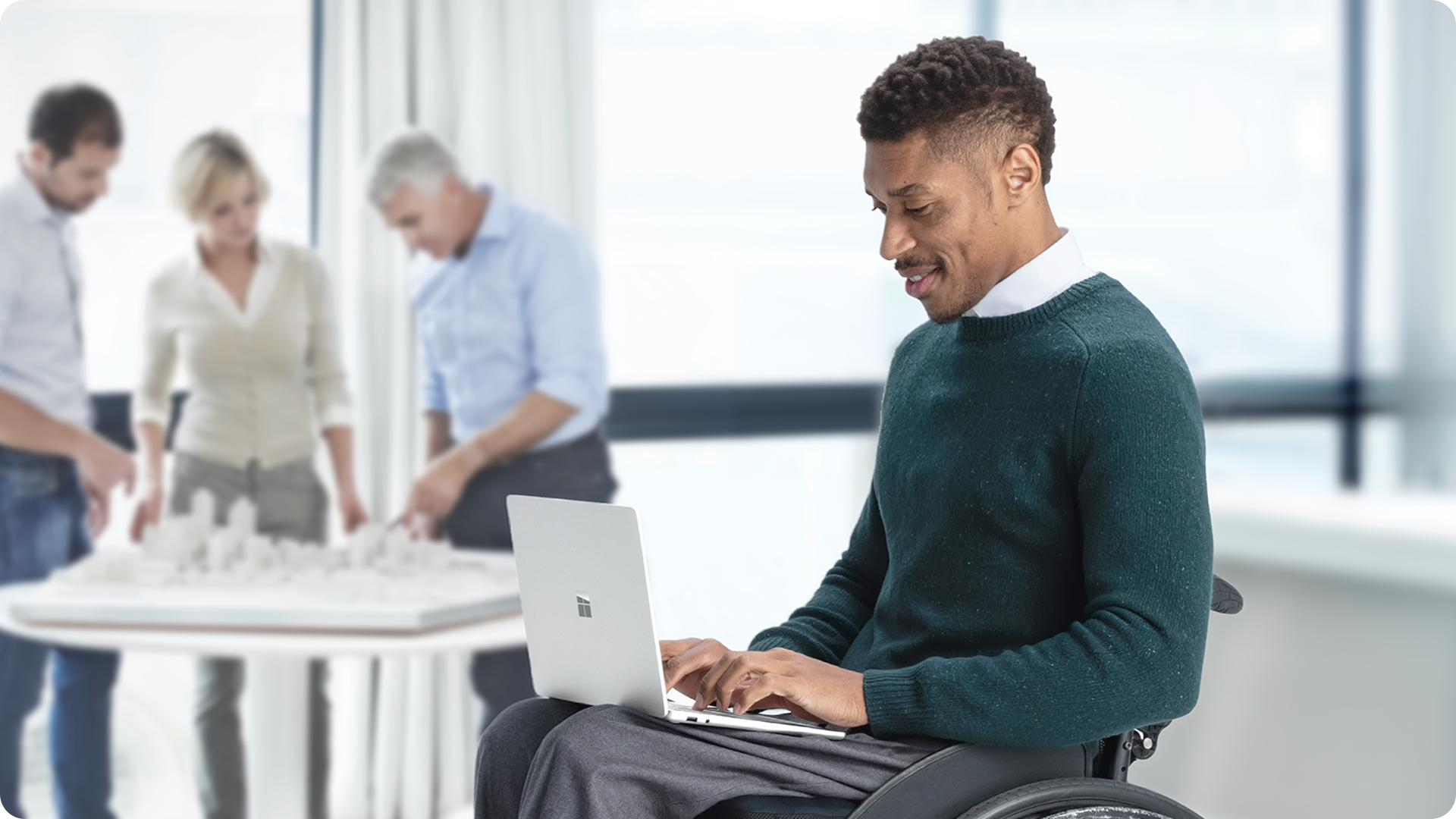一位坐在轮椅上的用户正在膝上的 Surface Laptop 商用版上打字。