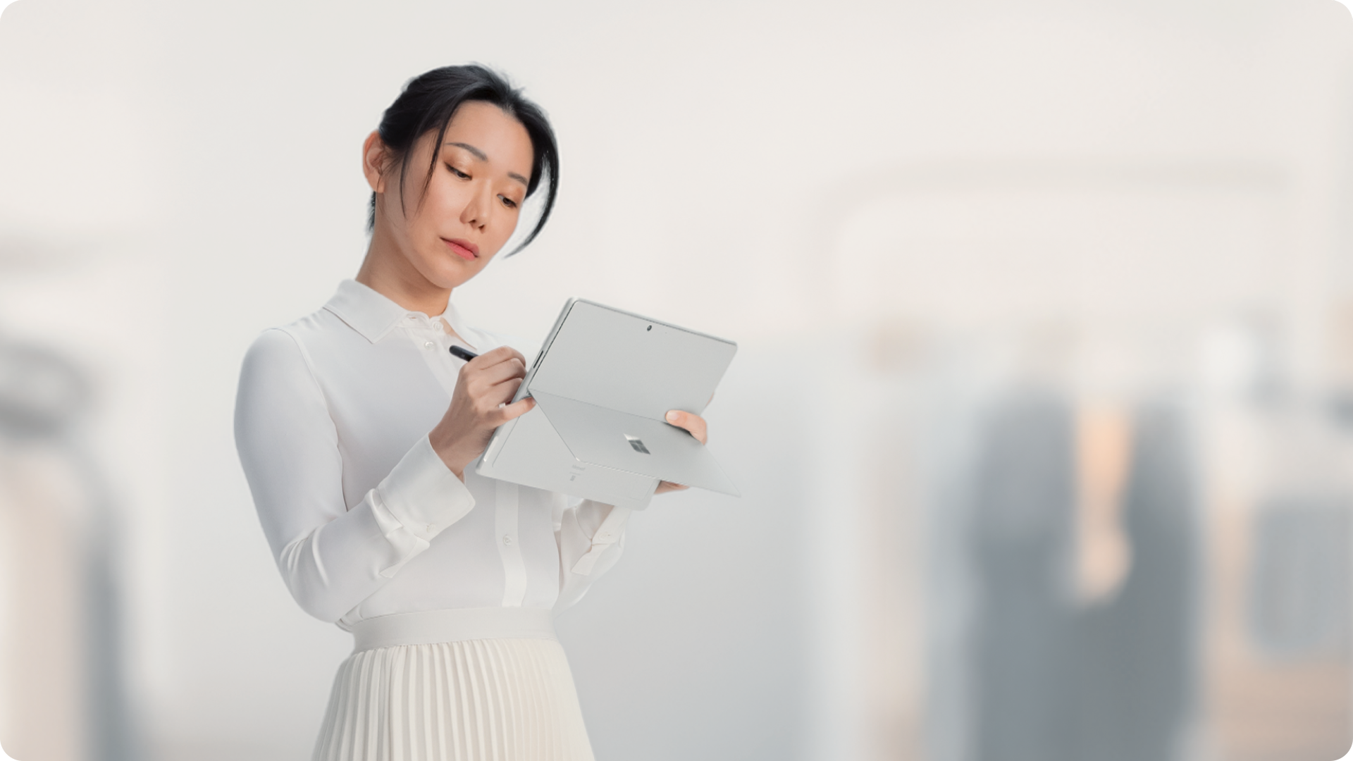 用户手持 Surface Pro 商用版，使用超薄手写笔在触控屏上书写。