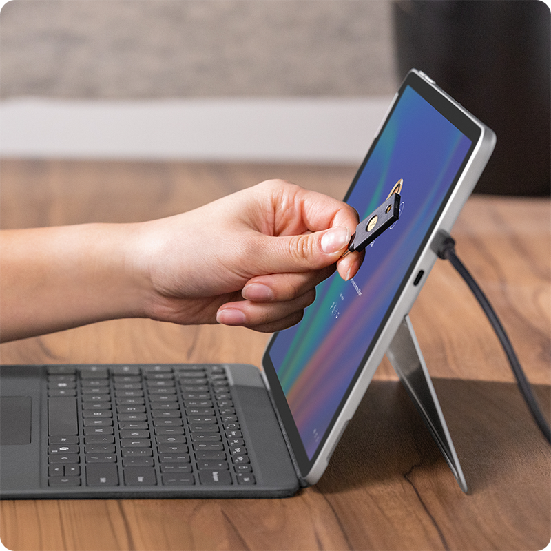 用户将 NFC 工牌轻触 Surface Pro 商用版显示屏，实现快速安全登录。